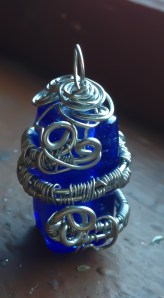 A royal blue rectangular piece of glass is wrapped in woven silver wire - a very intricate piece!